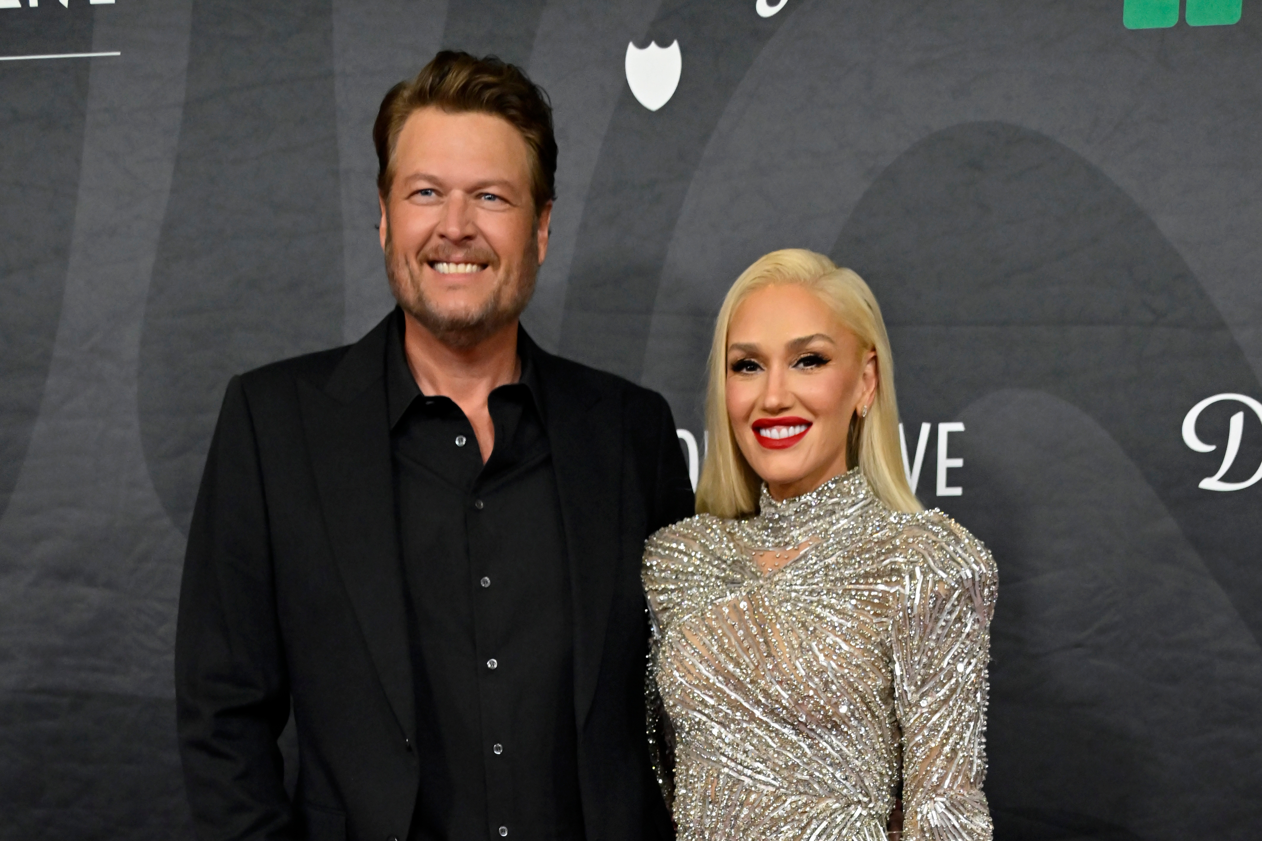 Blake Shelton and Gwen Stefani smiling connected  the reddish  carpet. One idiosyncratic   is wearing a acheronian  suit, and the different   is successful  a sparkling, embellished dress