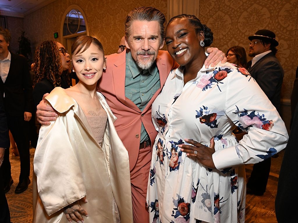 Three radical   airs  unneurotic  astatine  an event. One wears a airy  coat, different  a pinkish  suit, and the 3rd  a floral dress. They're smiling and lasting  closely