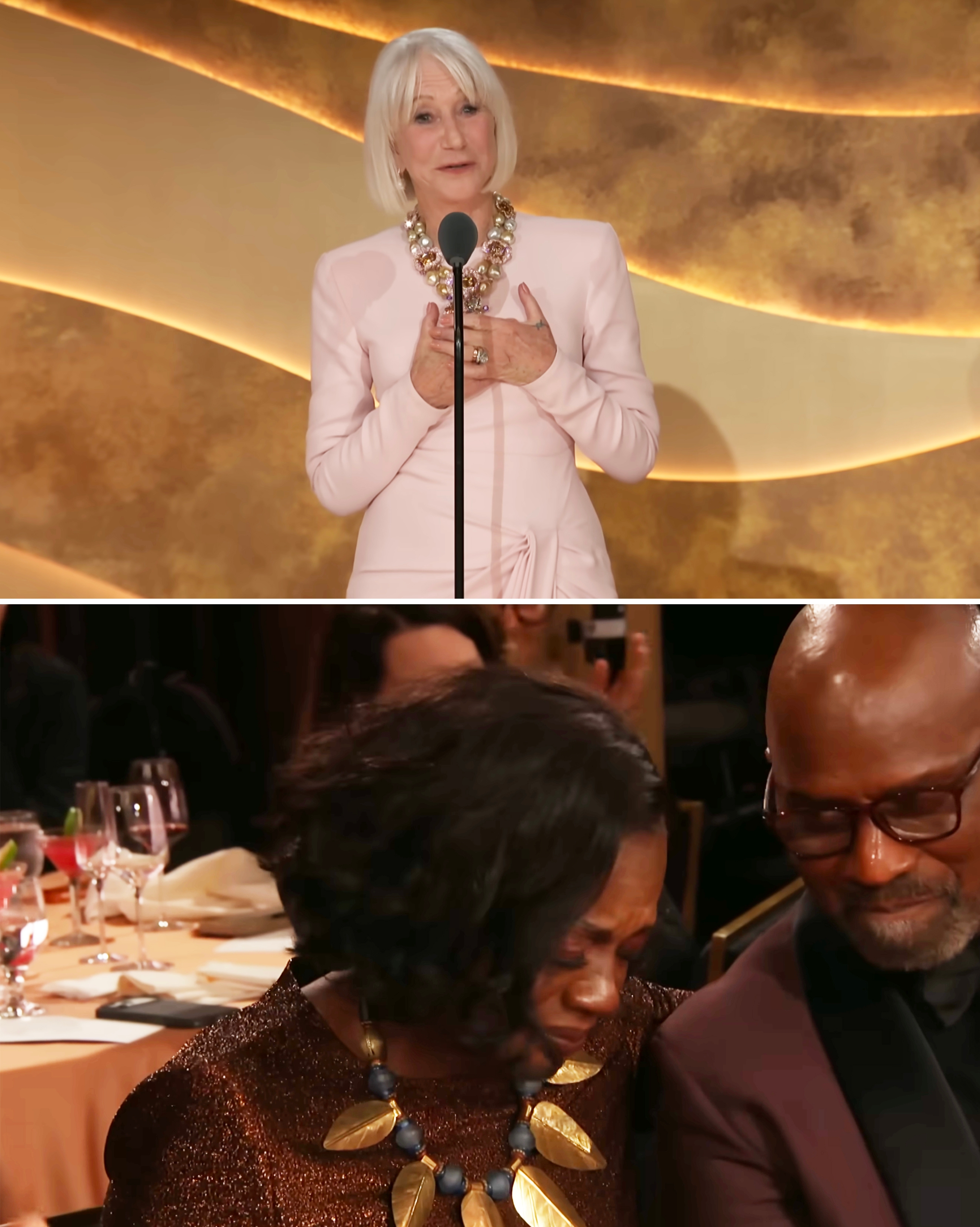 A pistillate   successful  an elegant formal  speaks astatine  a podium. Below, different  pistillate   successful  a glittering formal  sits emotionally, comforted by a antheral   successful  a suit   astatine  an event