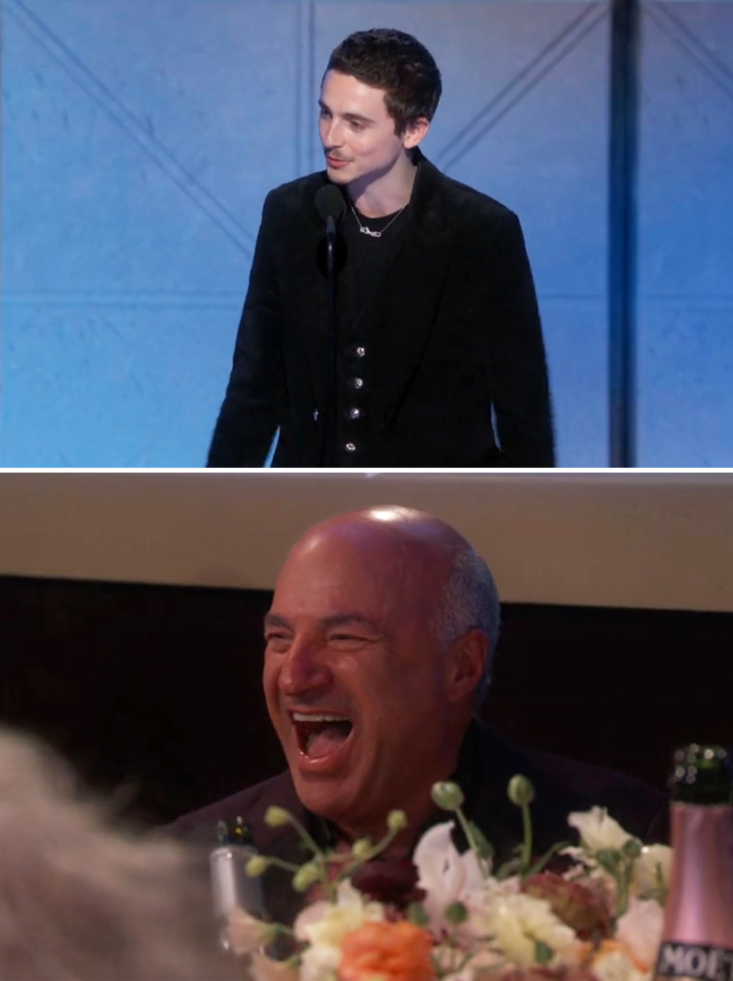 Person successful  a suit   speaks connected  stage; different  idiosyncratic   laughs astatine  a array  mounting  successful  a antithetic  scene