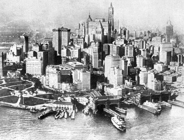 Pemandangan udara cakrawala Kota New York awal abad ke-20, menampilkan gedung pencakar langit yang padat dan dermaga yang sibuk di sepanjang tepi laut