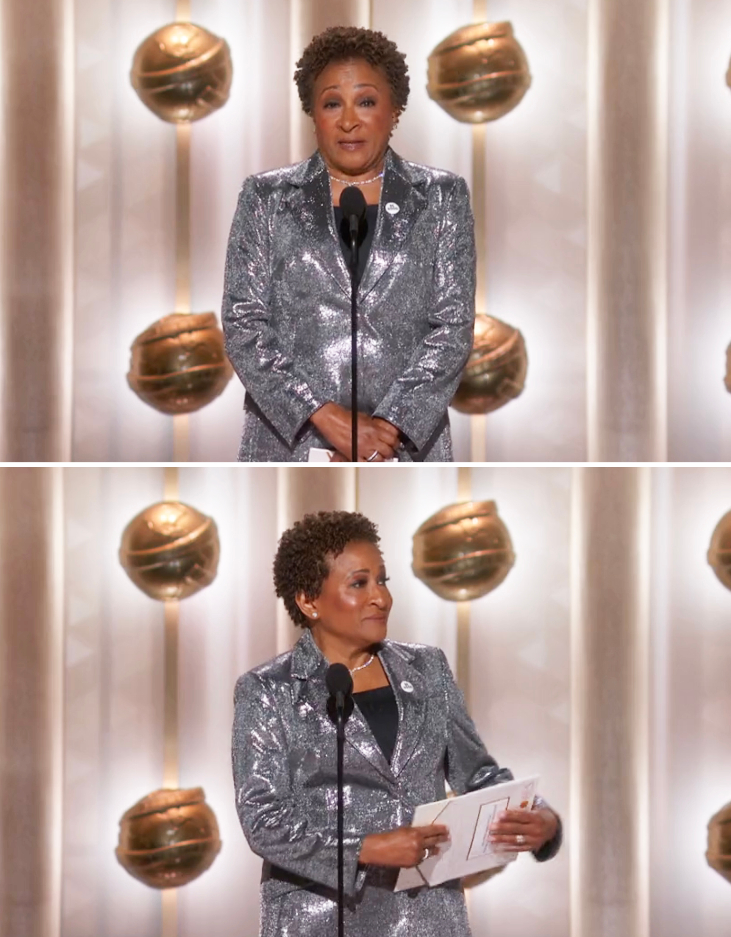 Person connected  signifier    wearing a shiny suit, holding papers, and speaking astatine  an awards event. Background shows decorative globe-like shapes