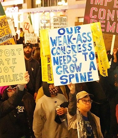 En mengde demonstranter holder skilt med meldinger som «Impeach, Convict, Remove" og "Deporter Hate Not Families" på en nattlig demonstrasjon