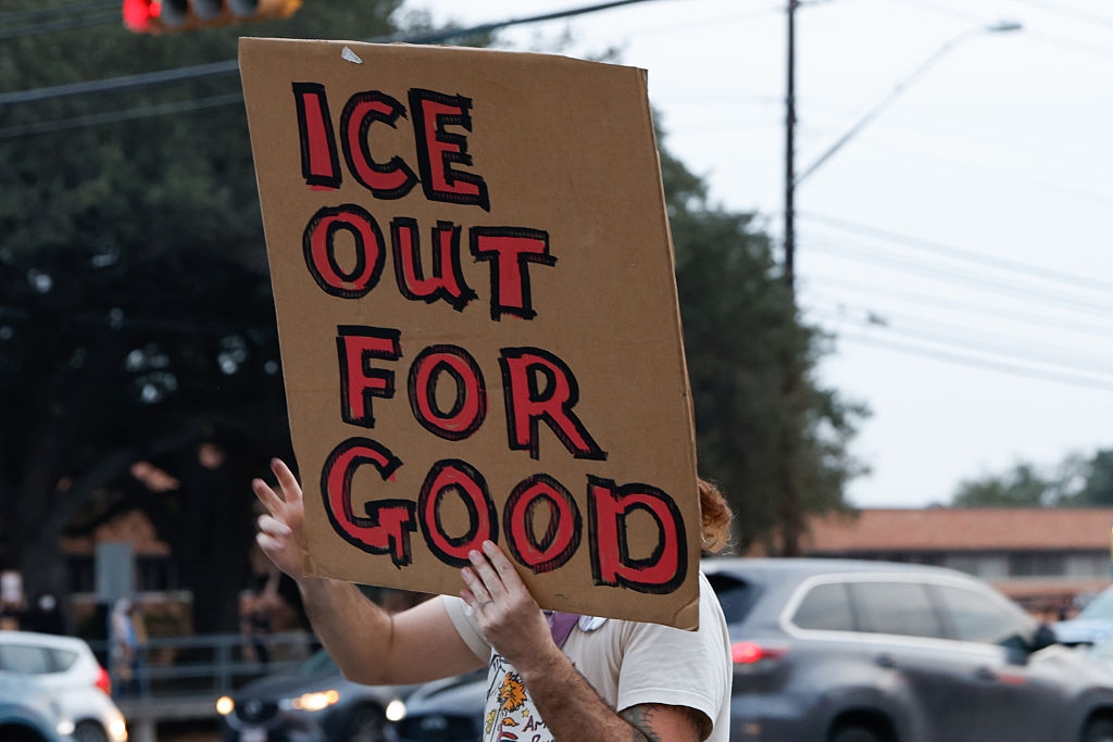 Person holder et protestskilt med teksten 