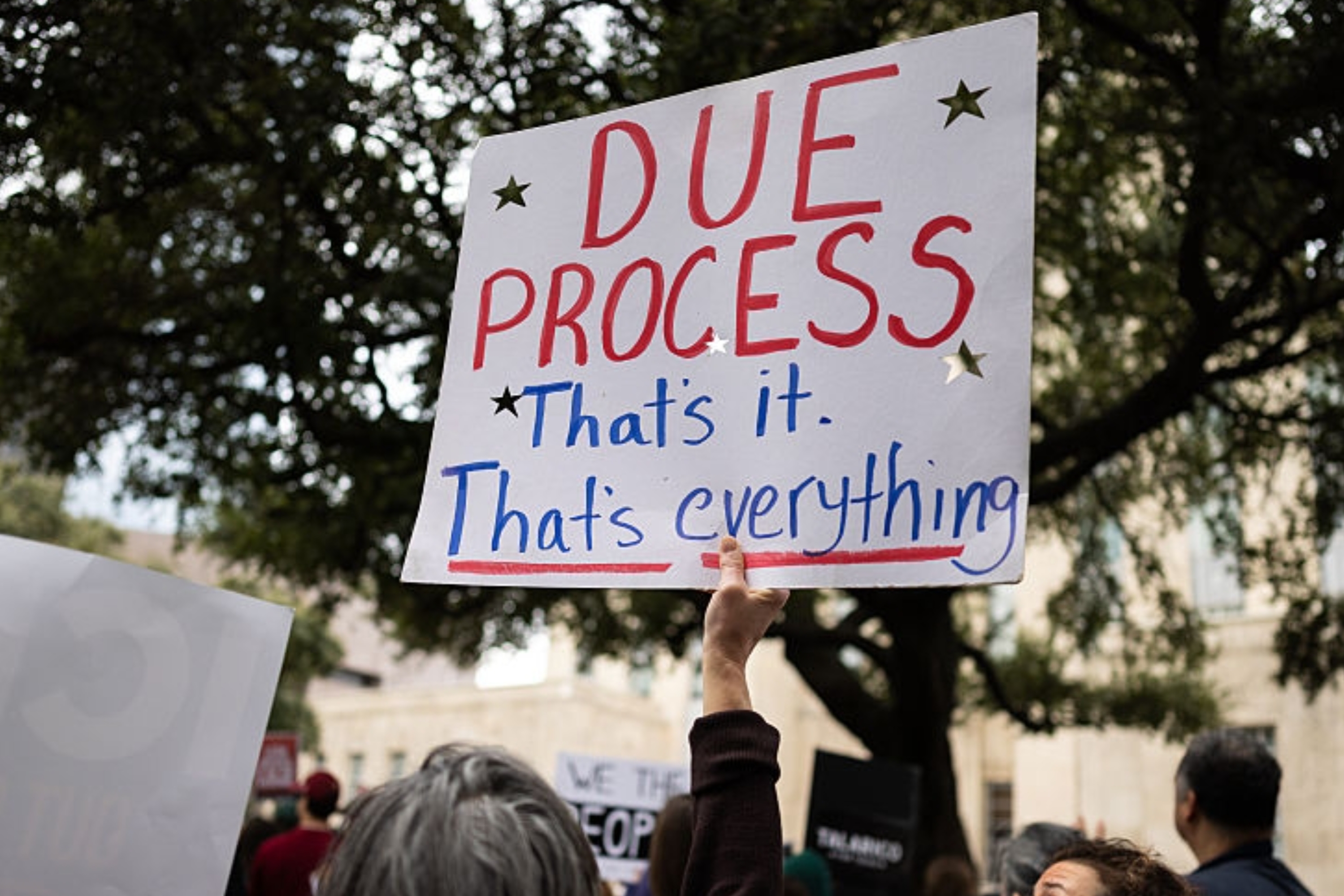En gruppe mennesker på en protest, med en person som holder et skilt med teksten «Due Process». Det er det. Det er alt."