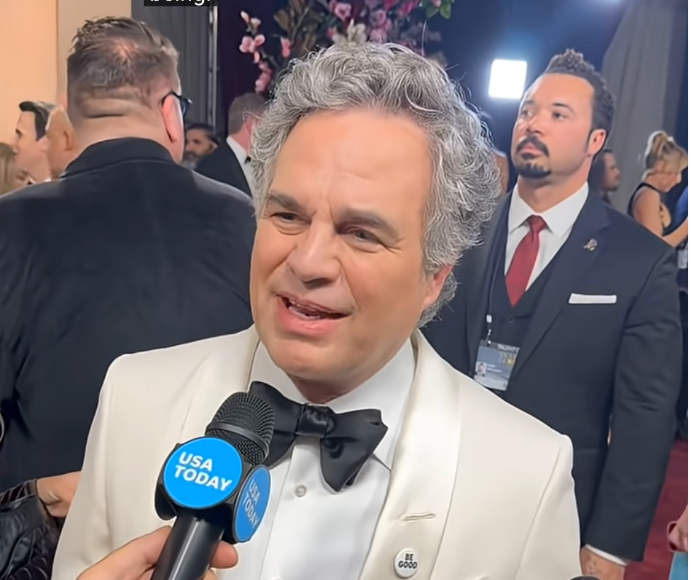 A idiosyncratic successful a achromatic tuxedo speaks to a USA Today newsman astatine a ceremonial lawsuit with radical and cameras successful the background