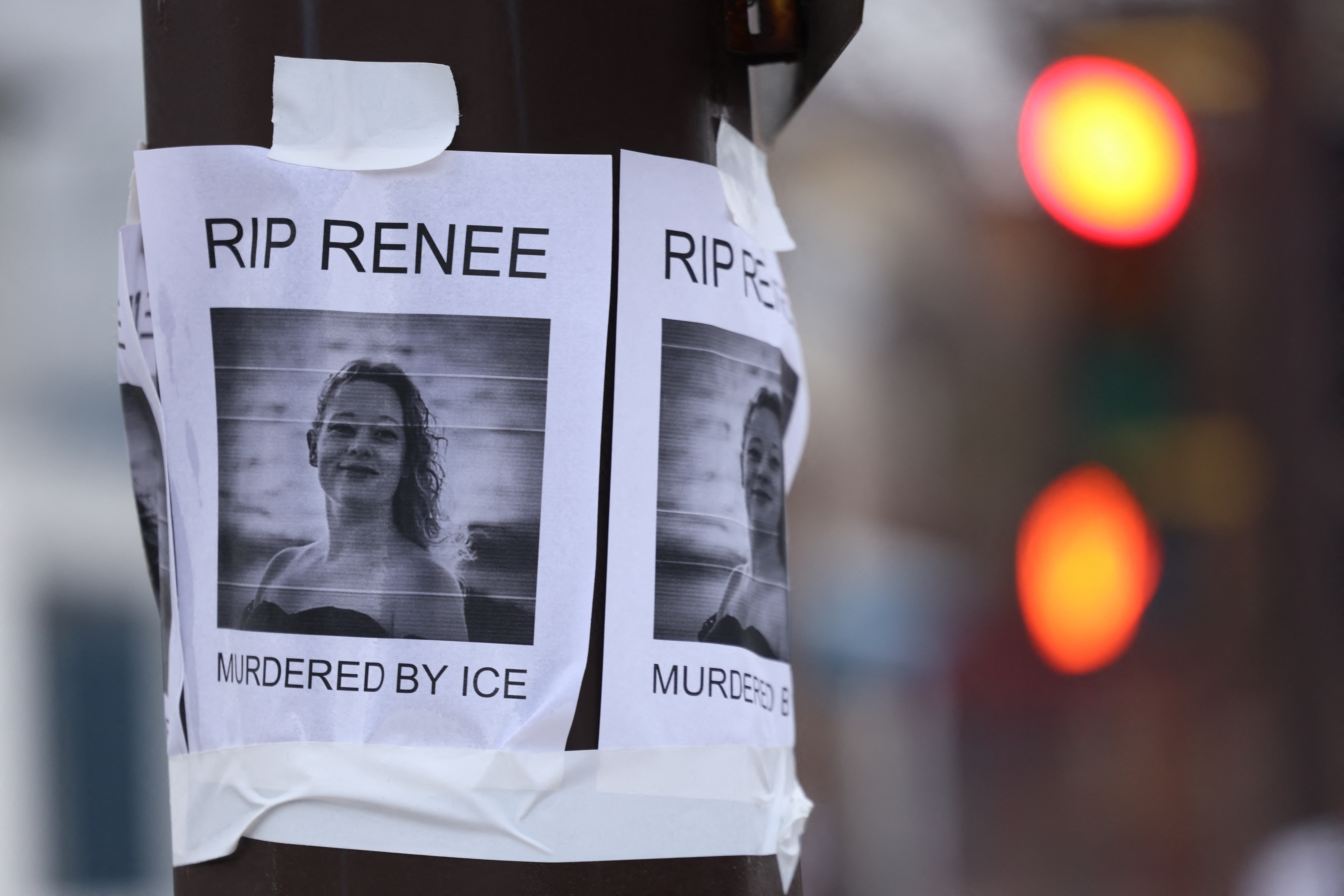 Flyers taped to a rod diagnostic a photograph of a pistillate and the messages "RIP Renee" and "Murdered by ICE."