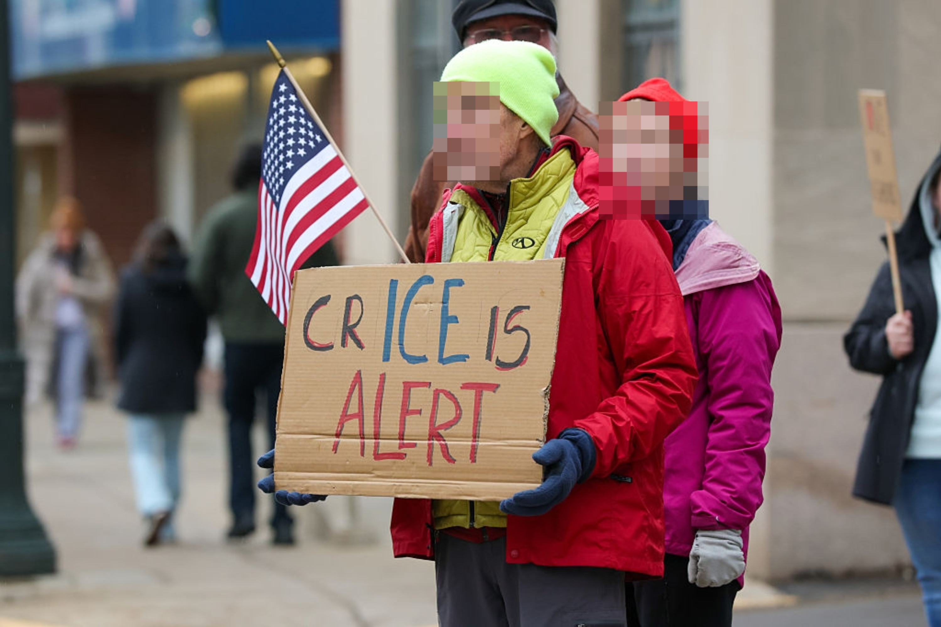 Folk står på gaten og holder et pappskilt med teksten 