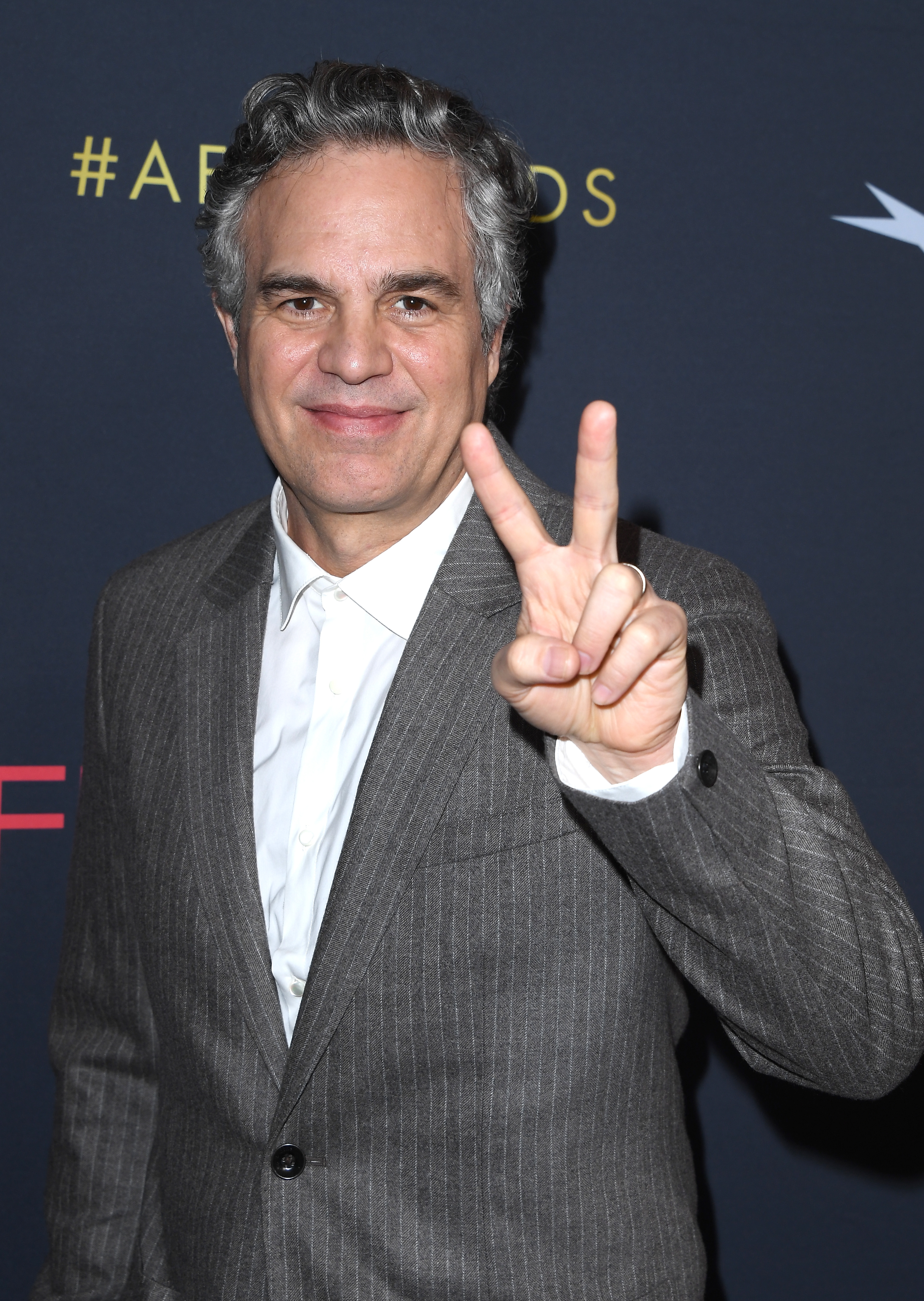 Person successful a grey suit holds a bid motion connected a reddish carpet, smiling