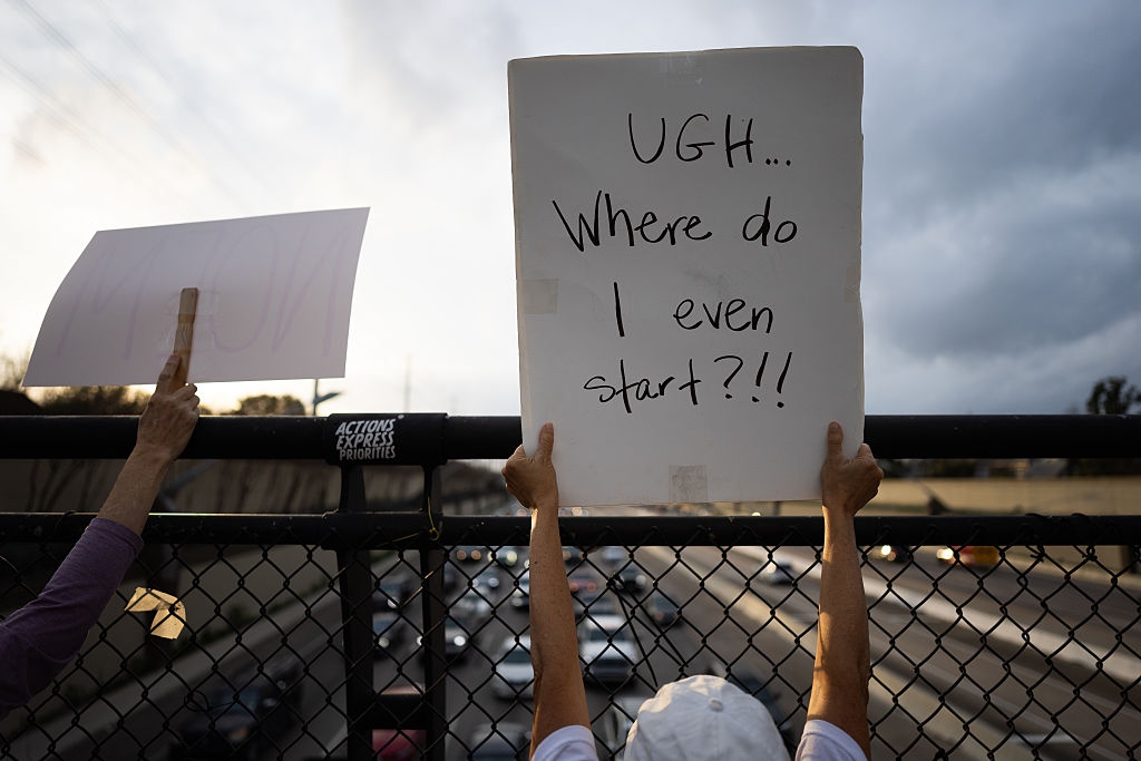 Folk som holder protestskilt over en motorvei. På ett skilt står det: 