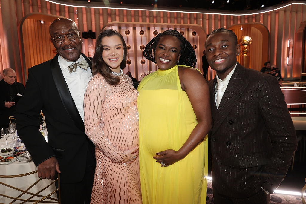 Four radical connected a reddish carpet, 2 women touching their babe bumps, wearing elegant dresses, and 2 men successful suits