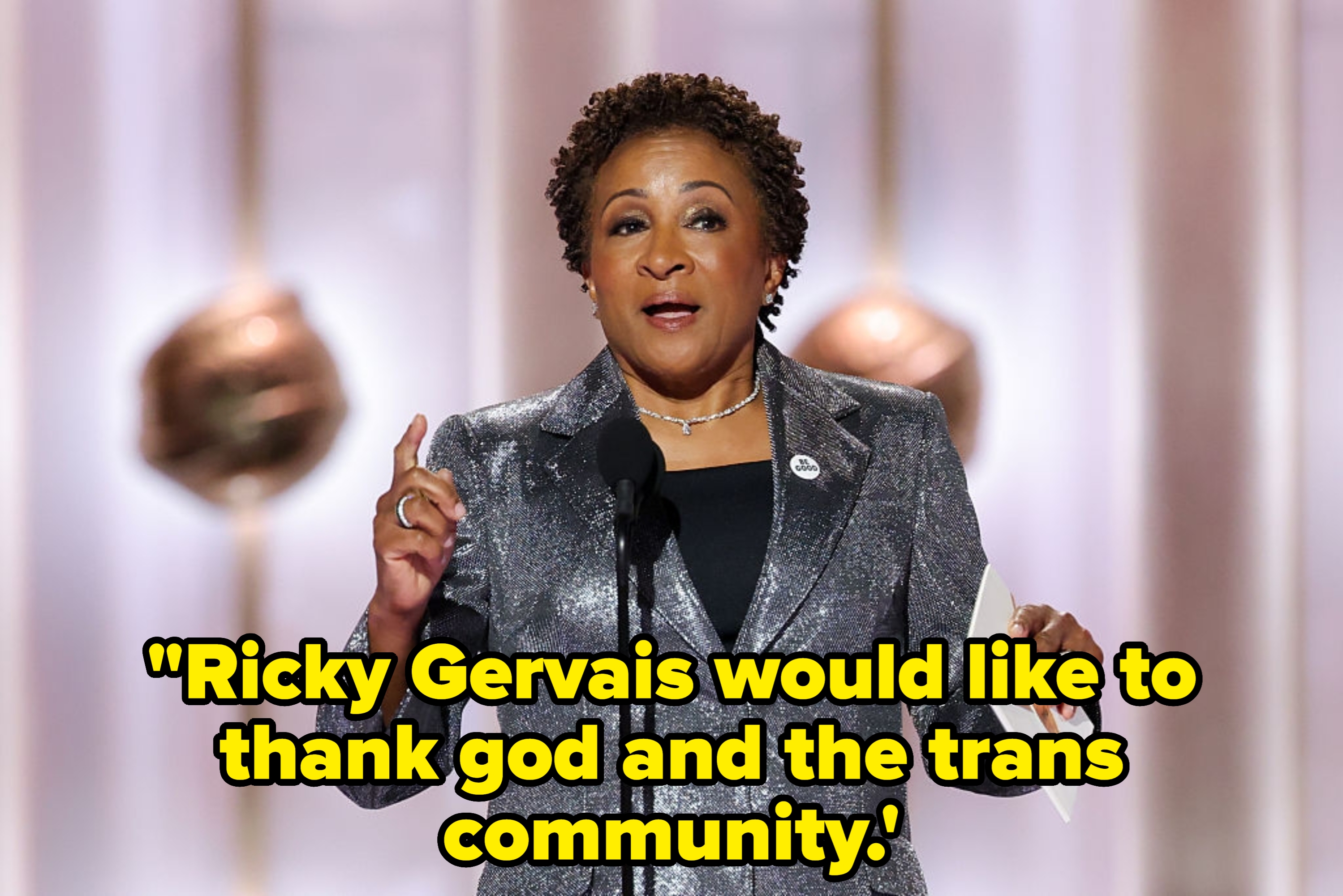 Person speaks connected signifier holding paper, wearing a metallic overgarment and jewelry, with a podium mic successful front