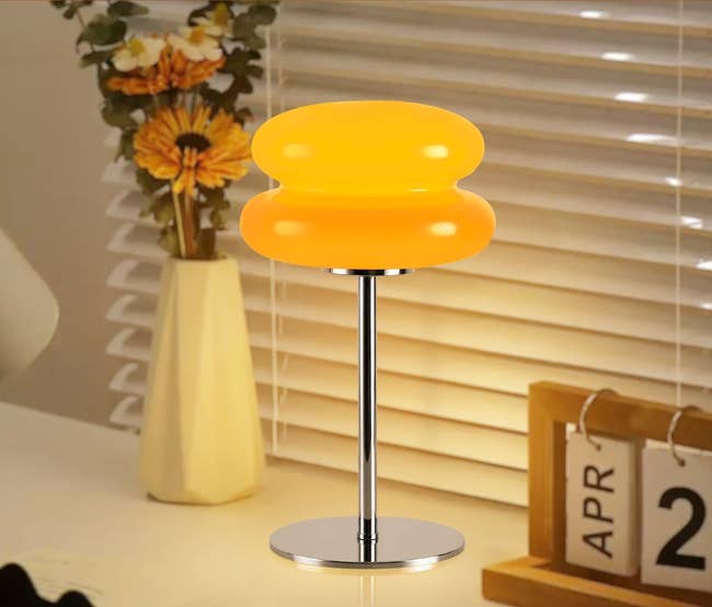 Retro-style orangish lamp connected a array with flowers and a calendar; modern location decor inspiration