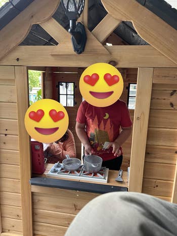 Two children play successful a woody playhouse; 1 stirs pots connected a artifact stove portion the different uses a artifact phone, engaging successful imaginative play