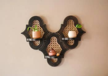 Wall support with 3 ornate tiers, displaying 2 tiny plants and 3 decorative candles