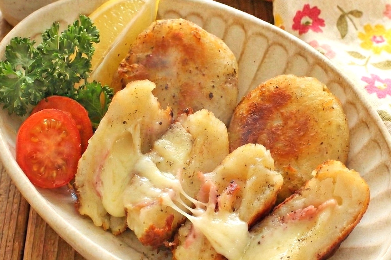 皿に盛られたポテトパンケーキと溶けたチーズ、トマト、レモン、パセリの添え物。