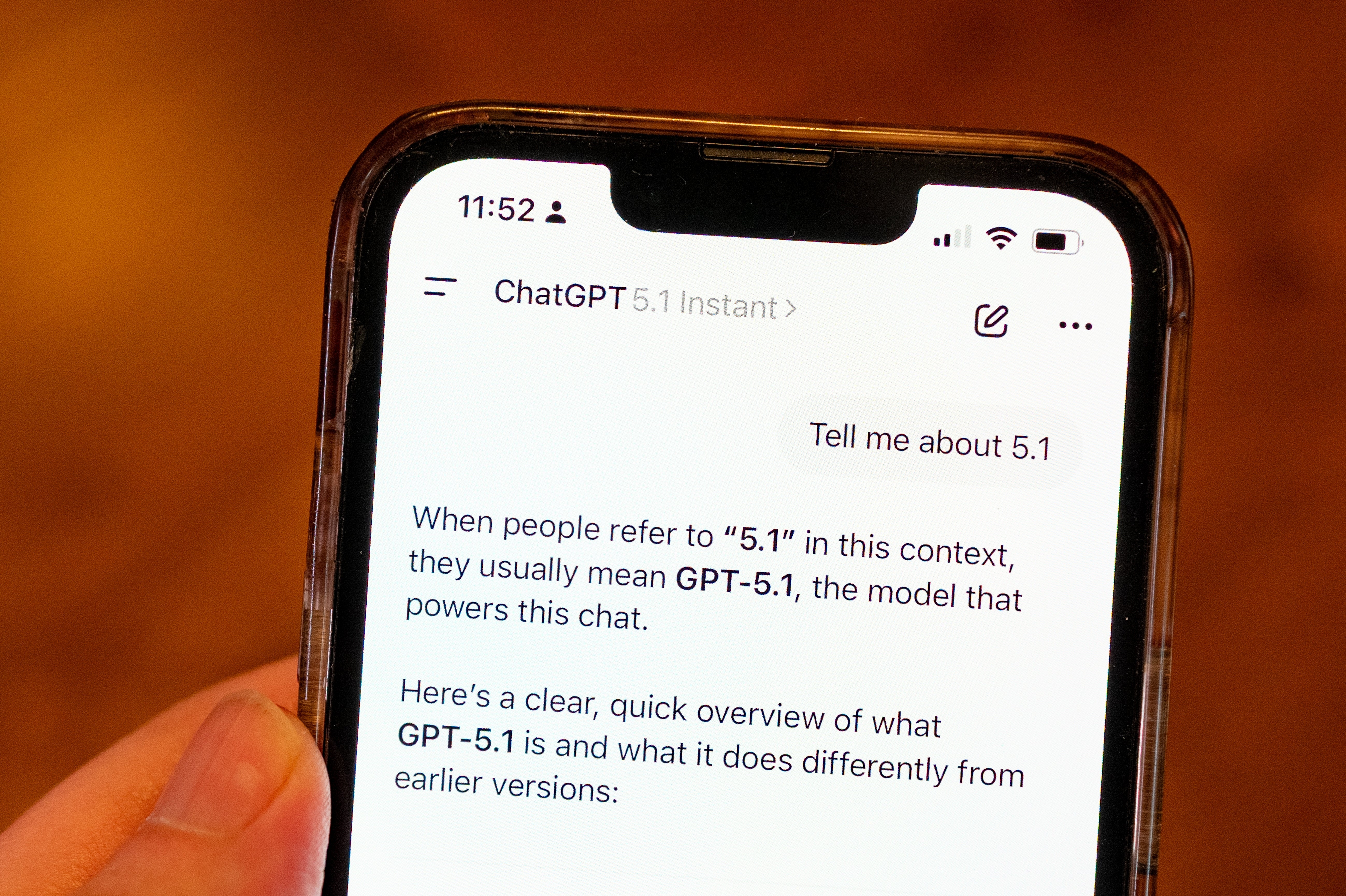 Nærbilde av en telefonskjerm som viser en chat med en beskrivelse av GPT-5.1-modellens forskjeller fra tidligere versjoner