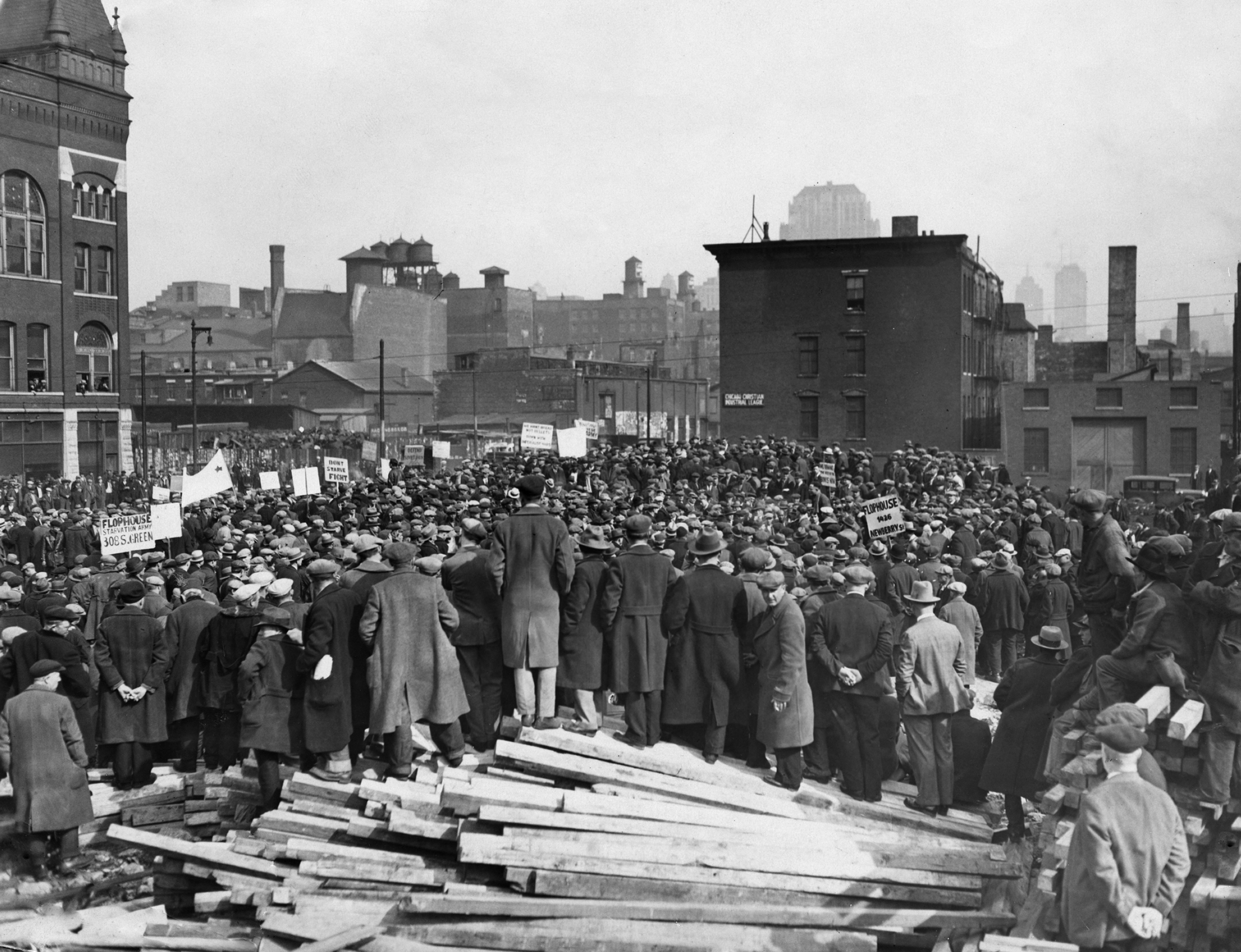 Historical photograph  of a ample  assemblage  gathered for a labour  rally successful  an municipality  setting, with a talker  addressing them from a heap  of woody  planks