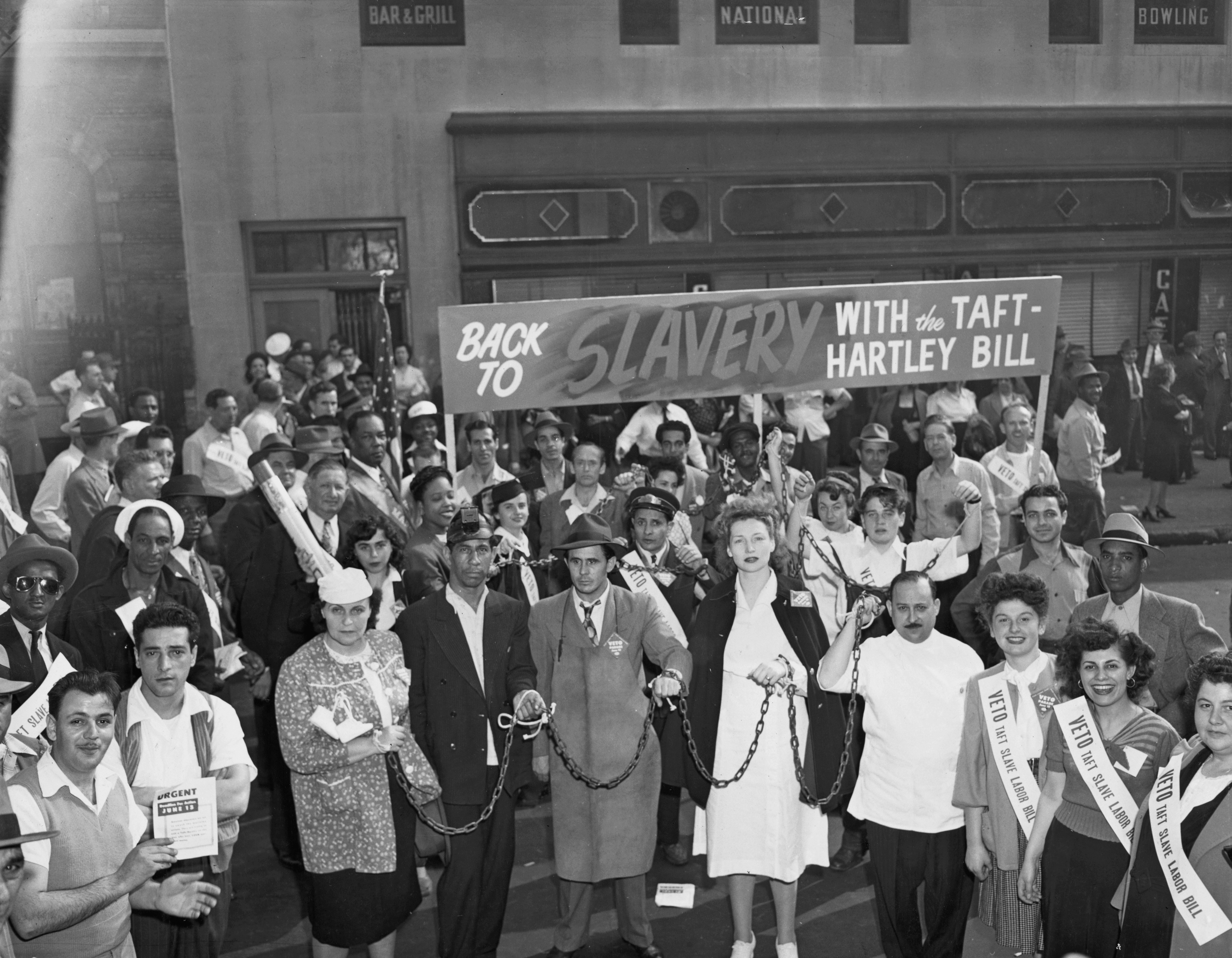 Historical protestation  country   with divers  radical  holding signs against the Taft-Hartley Bill, highlighting labour  rights and anti-slavery sentiments