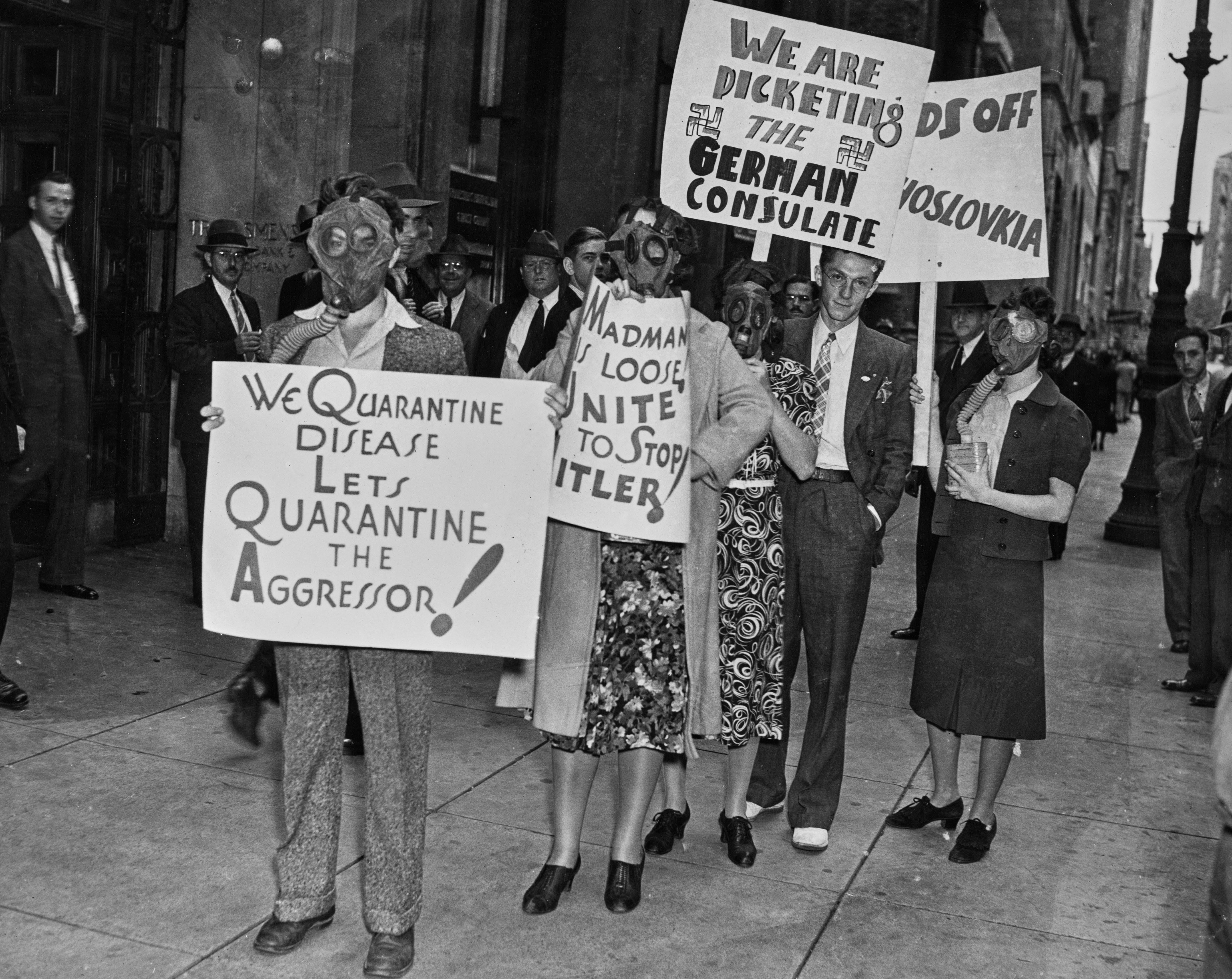 Protesters wearing state  masks clasp  anti-Hitler signs during a 1930s objection  extracurricular  a building