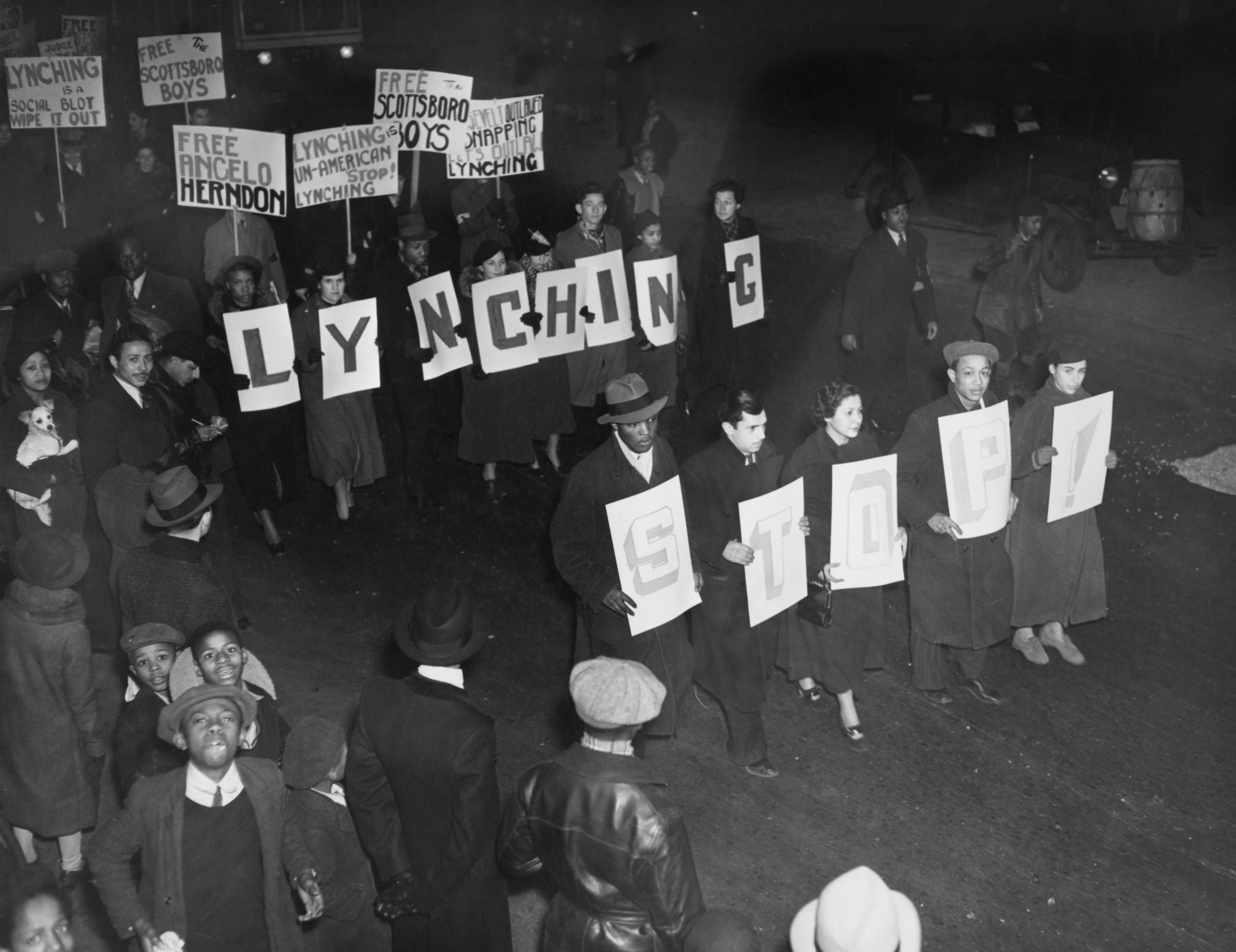 A radical  of protestors march astatine  nighttime  holding signs that work   "LYNCHING STOP" alongside different   signs advocating for justness  and freedom