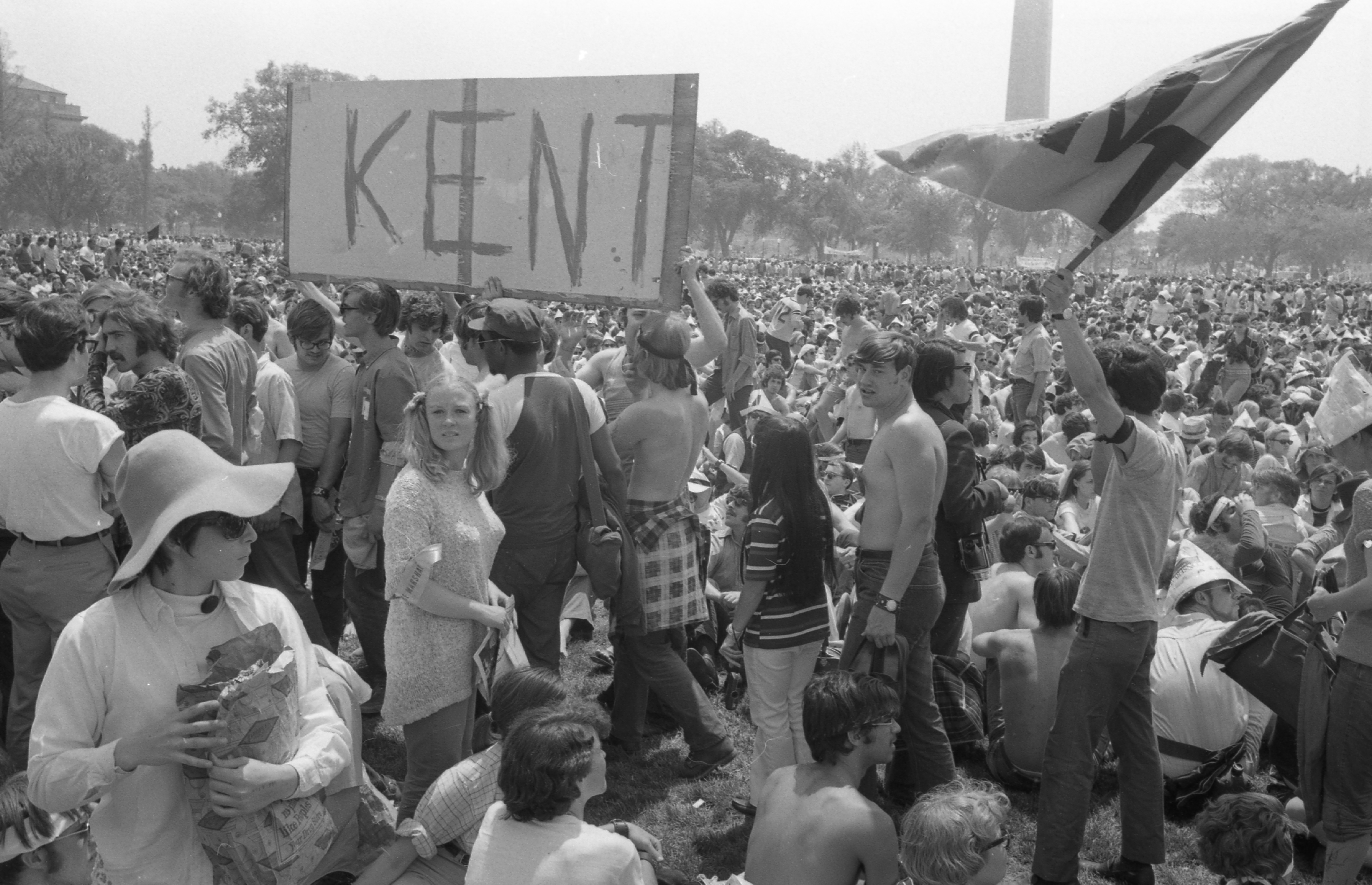 Crowd of protesters astatine  a demonstration, 1  idiosyncratic   holds a "KENT" sign. The ambiance  is tense and focused, with the Washington Monument visible