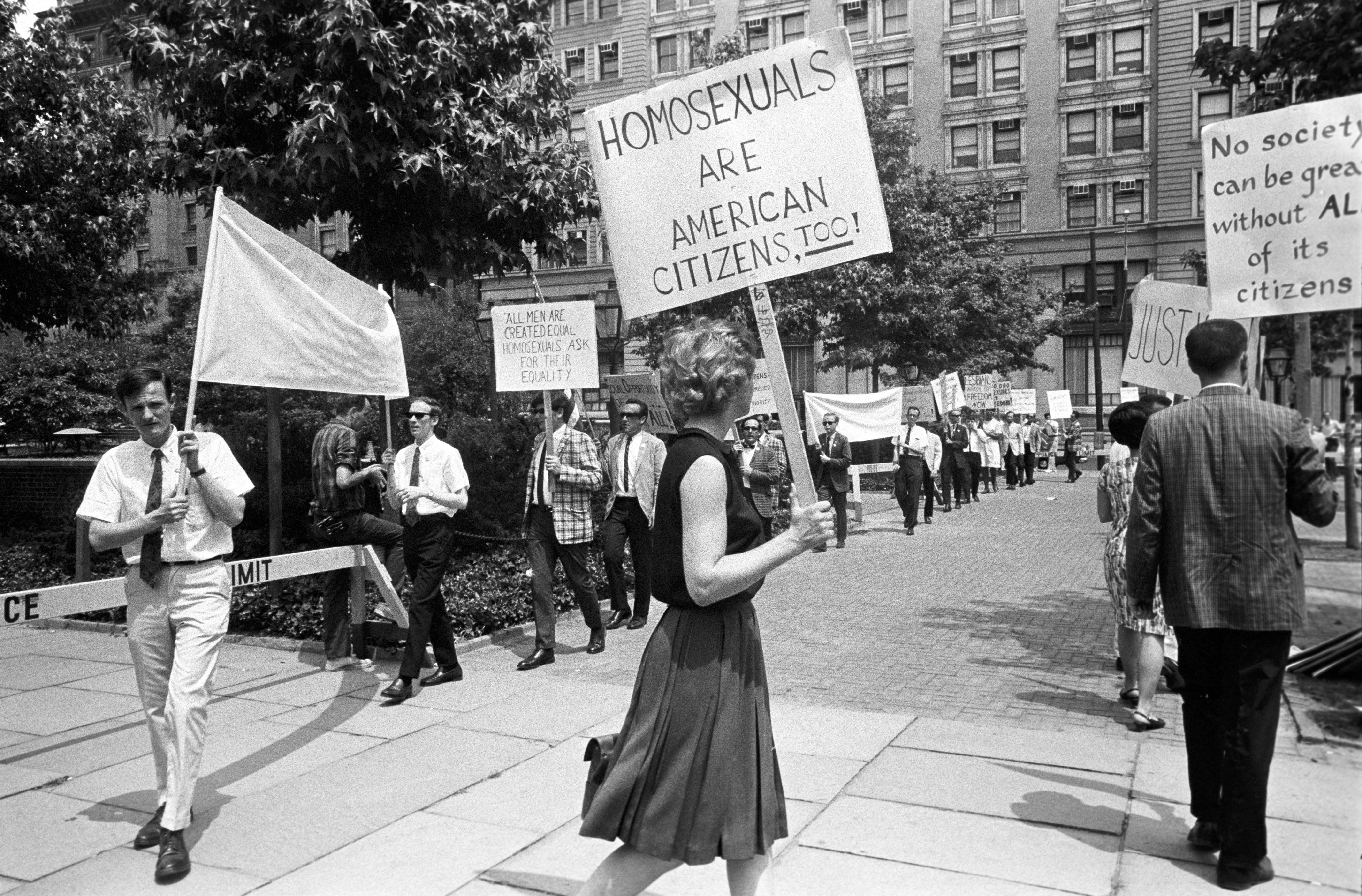 People protestation  successful  a metropolis  thoroughfare  with signs advocating for LGBTQ+ rights, including "Homosexuals are American Citizens Too!"