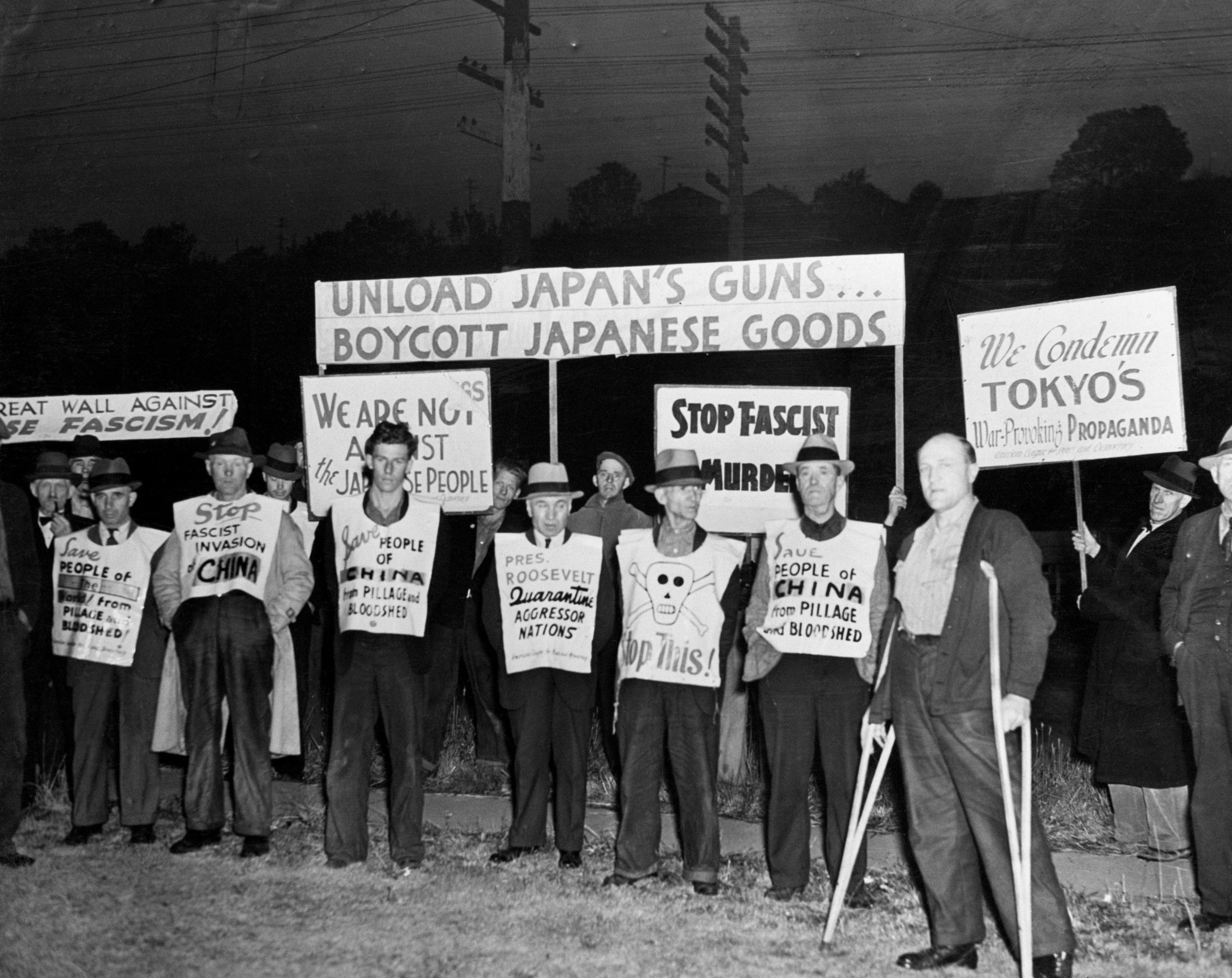 A humanities  protestation  with radical   holding signs advocating against Japanese goods and actions during wartime, highlighting anti-fascist sentiments