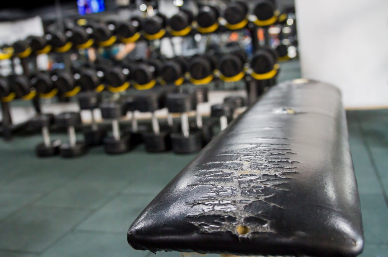 ジムのウェイトエリアにあるダンベルラックと傷んだベンチ。