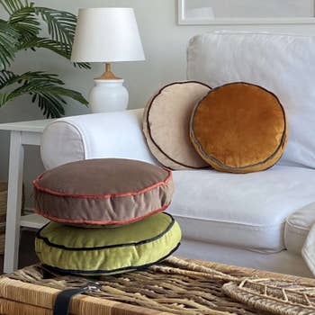 Round velvet pillows successful neutral tones arranged connected a achromatic sofa successful a cozy surviving country setting, with a wicker java array and a potted works nearby