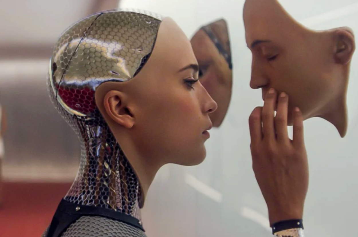 Person with metallic, futuristic appearance examines a human-like face mask