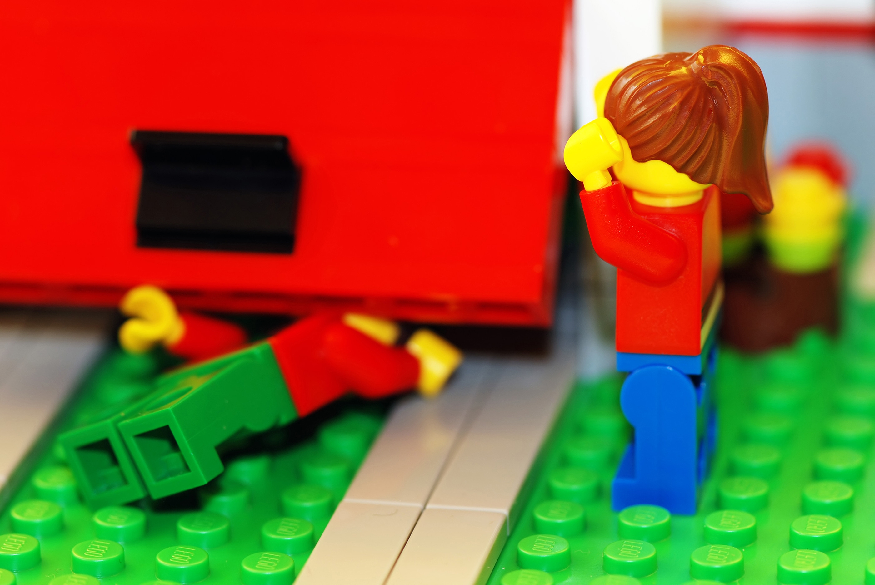 Two LEGO figures with one looking distressed near a fallen figure under a LEGO structure