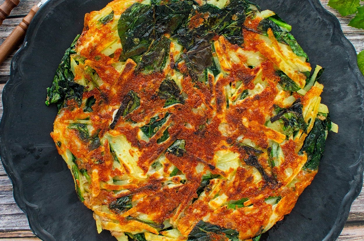 お皿に盛られた韓国風の野菜パンケーキ、具材に葉野菜が使われている。