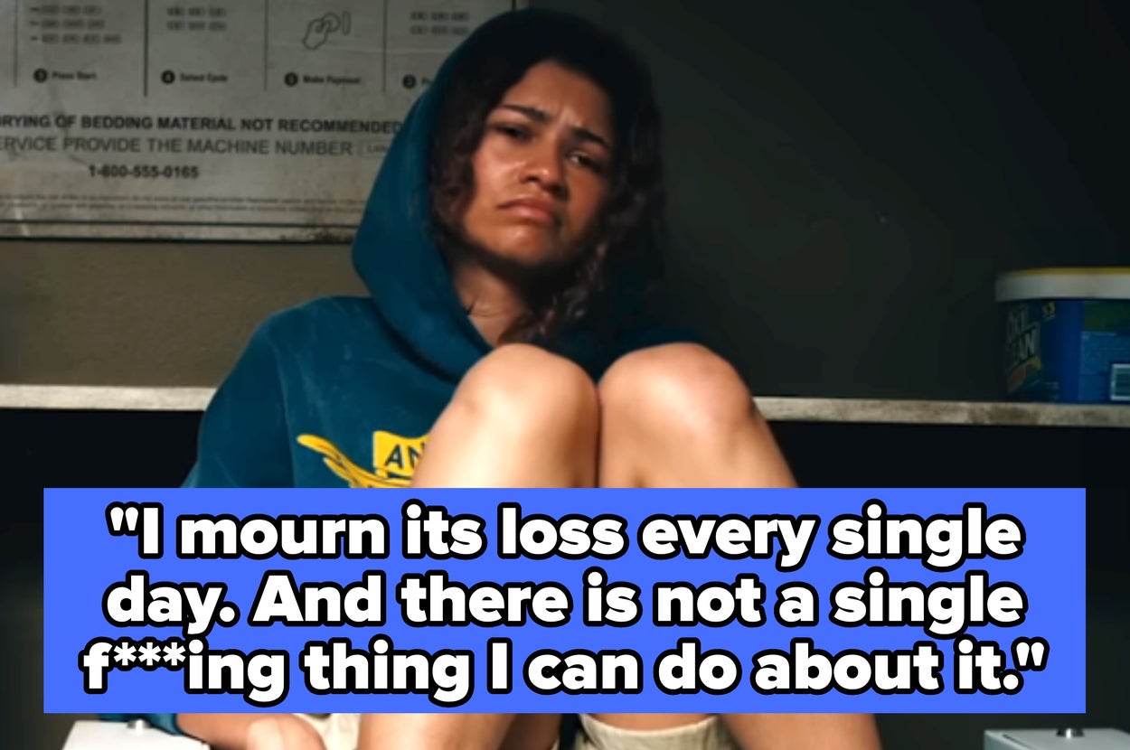 Person sitting on a laundromat counter, wearing a hoodie and shorts, with a pensive expression