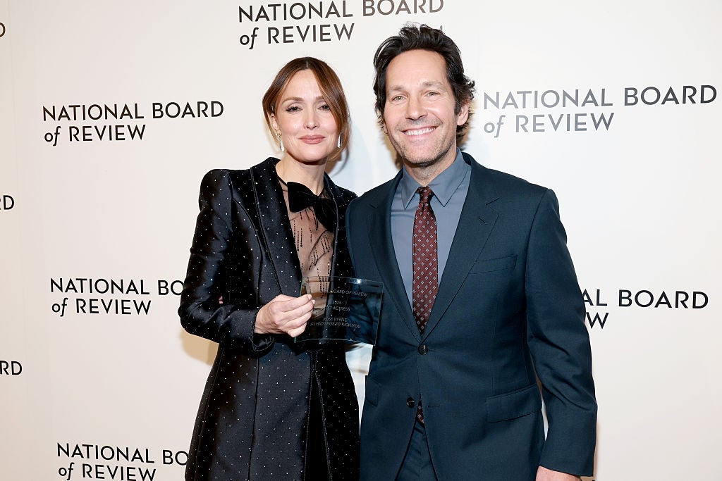 Dua orang berpose bersama di acara National Board of Review. Yang satu mengenakan setelan formal; yang lainnya, gaun bergaya. Mereka mengadakan penghargaan