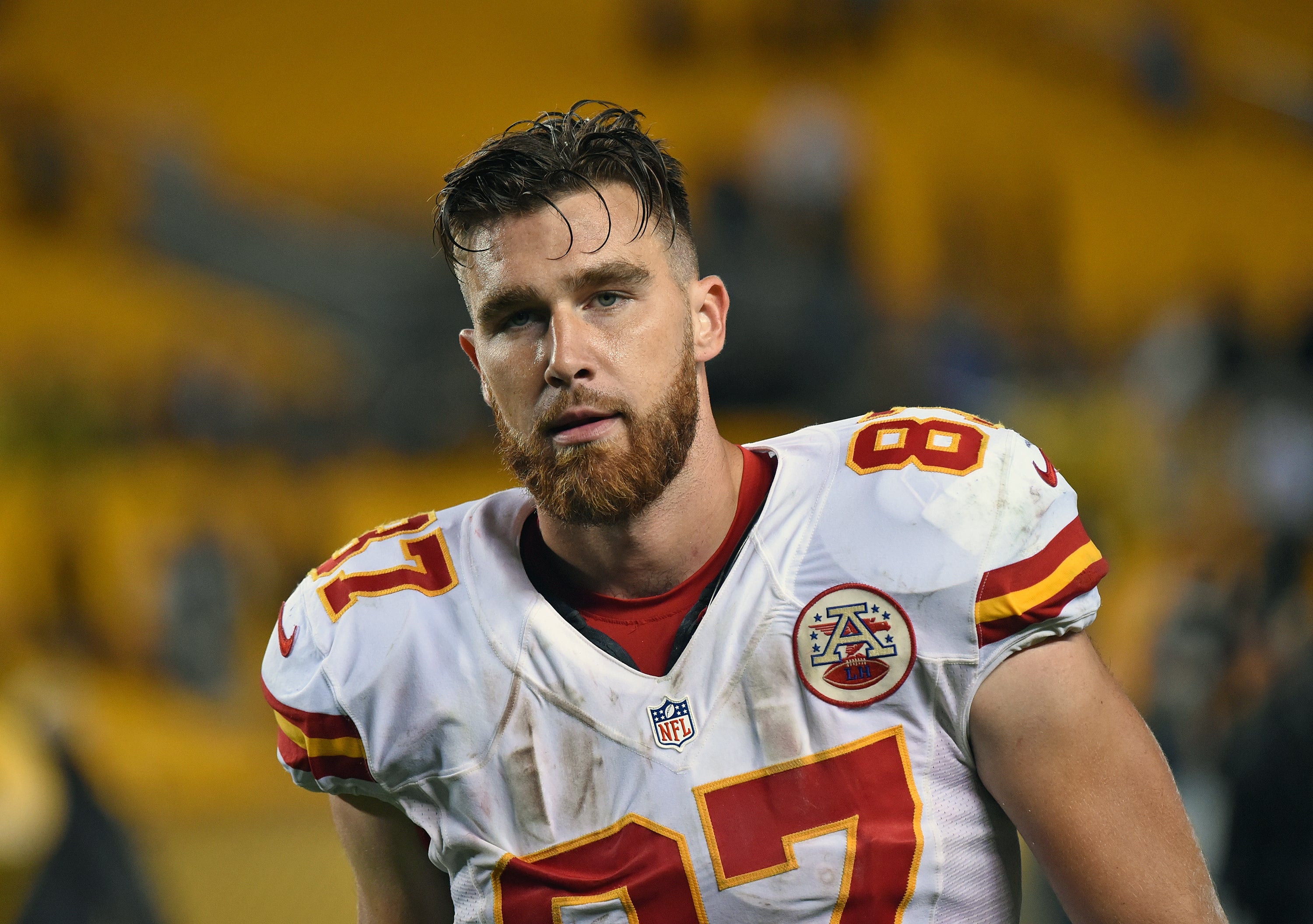 Seorang pemain sepak bola yang mengenakan jersey Kansas City Chiefs, nomor 87, muncul di lapangan sepak bola, tampak fokus
