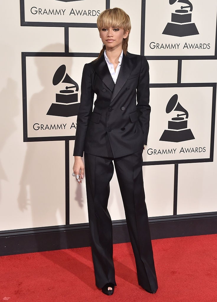 Seseorang dengan setelan double-breasted yang disesuaikan dengan celana lebar di karpet merah di latar belakang acara Grammy Awards