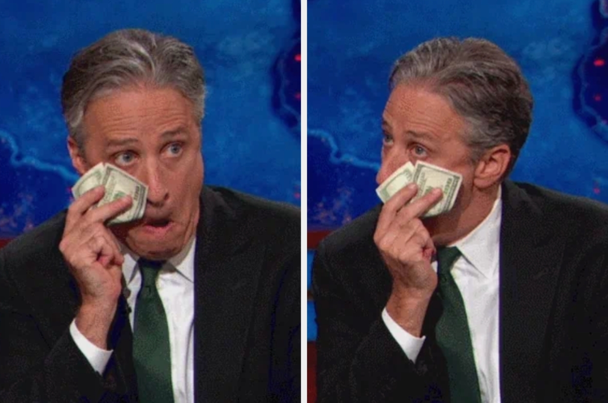A person humorously uses money as a tissue against their face, appearing to pretend to cry