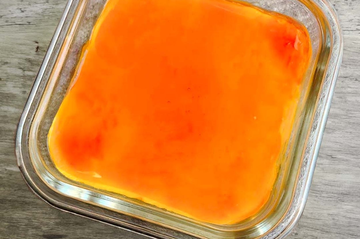 ガラス容器に入ったキャラメルソースがかかったプリンとスプーンがテーブル上に置かれている。