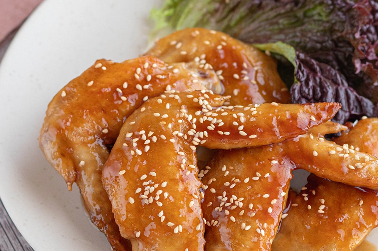 皿に盛られた照り焼きチキンウィング、ゴマがかかり、レタス付き。