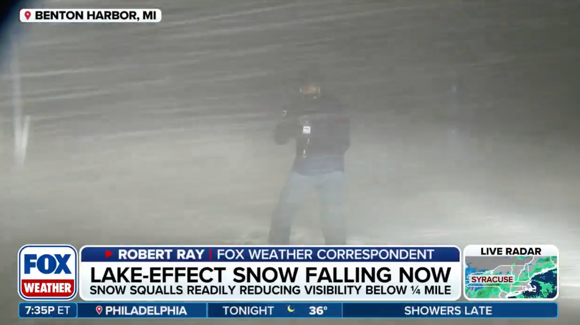 豪雪の中でレポートをする記者。視界がほとんどない状況を伝えている。