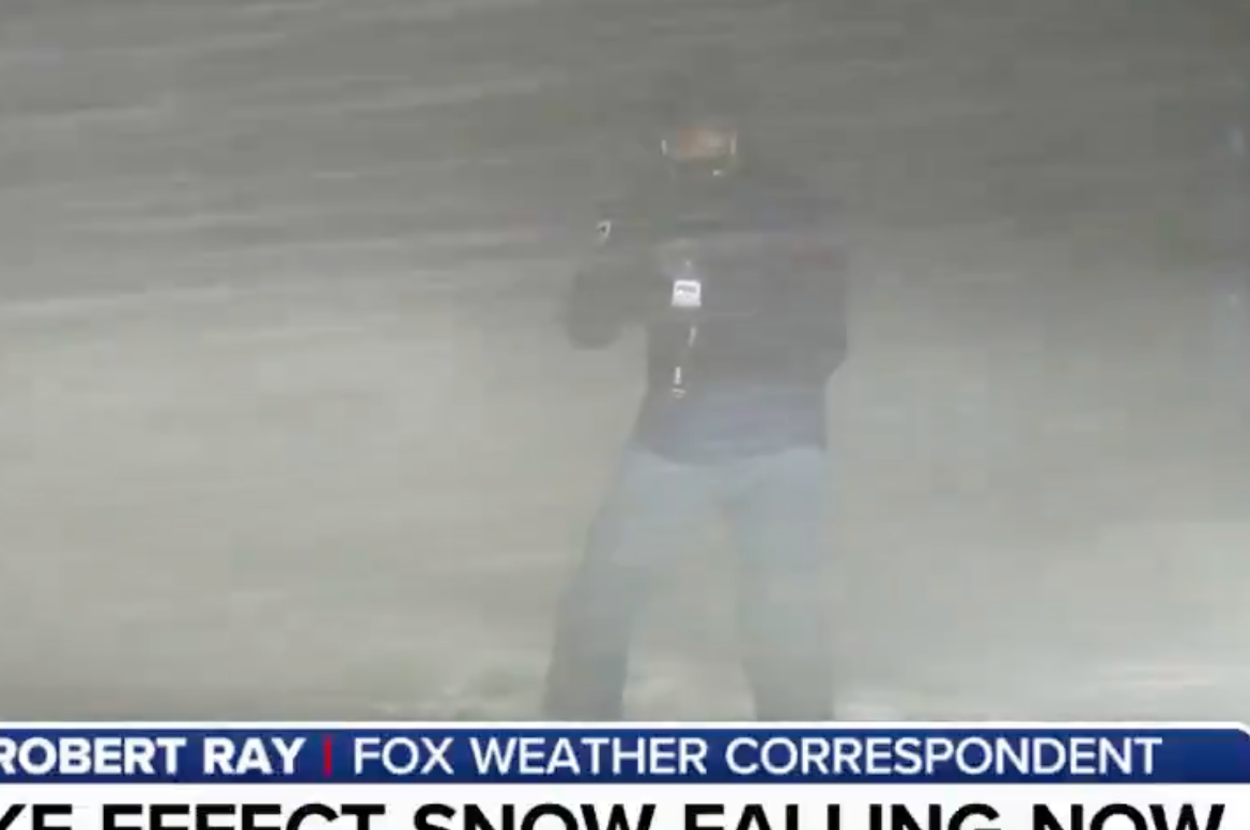 豪雪の中でレポートをする記者。視界がほとんどない状況を伝えている。