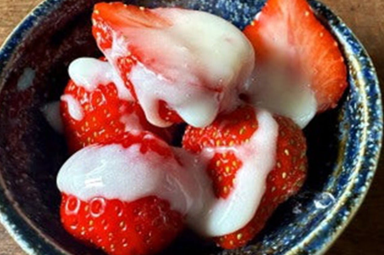 イチゴにクリームがかかった小さな器に盛られたデザート。