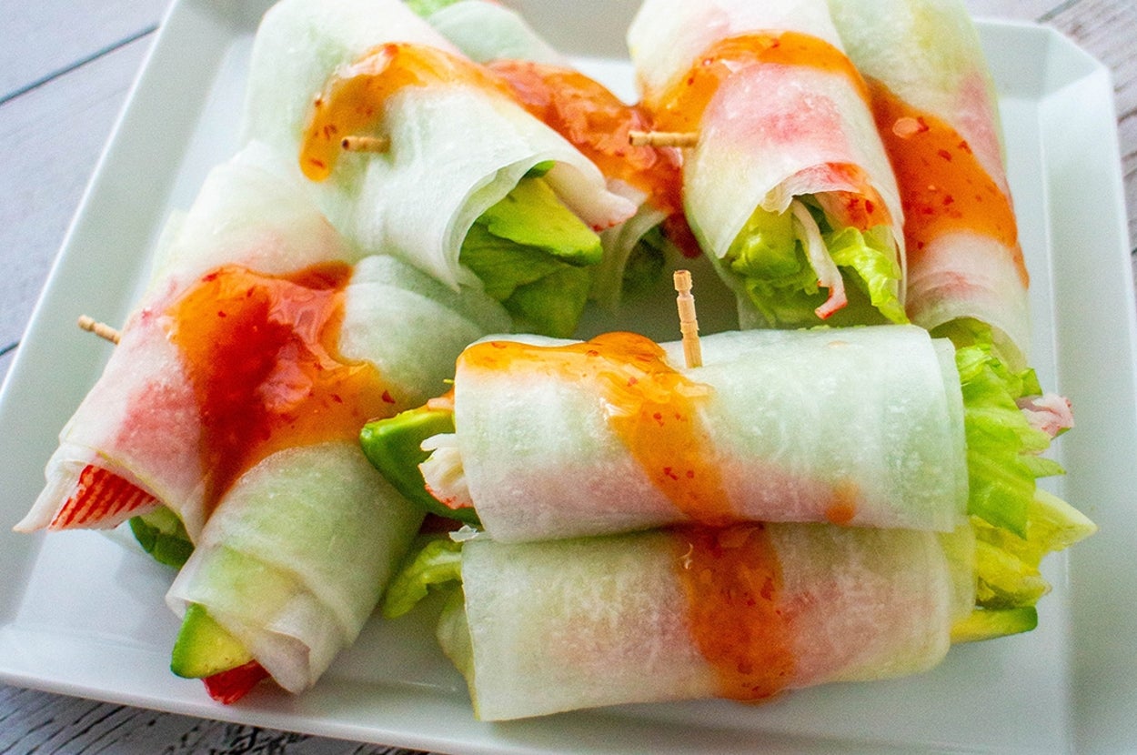 野菜とカニカマをライスペーパーで巻き、甘辛ソースがかかった前菜が白い皿に盛られている。