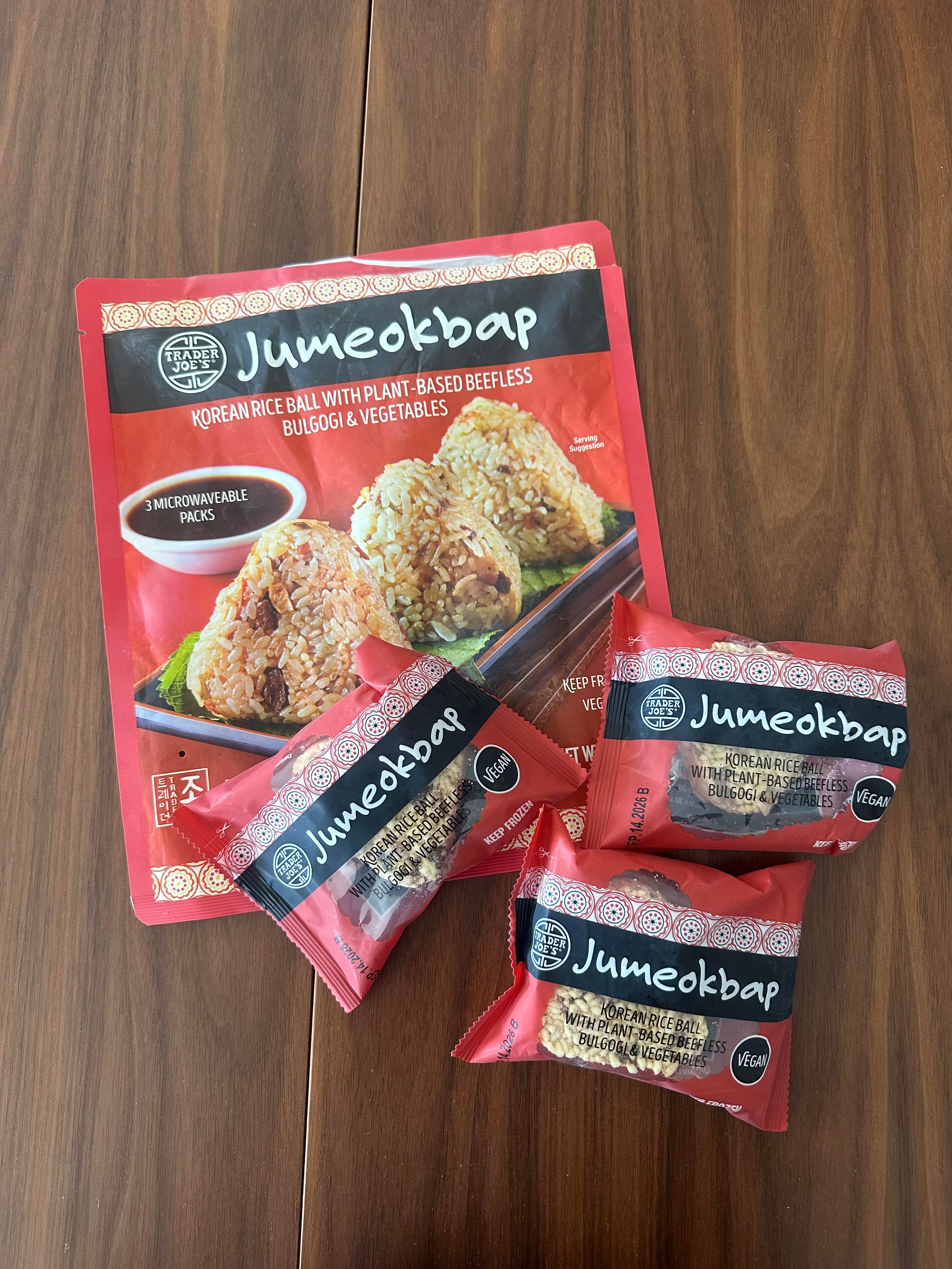 Packages of Jumeokbap, Korean rice balls with plant-based beefless bulgogi and vegetables, sit on a wooden table