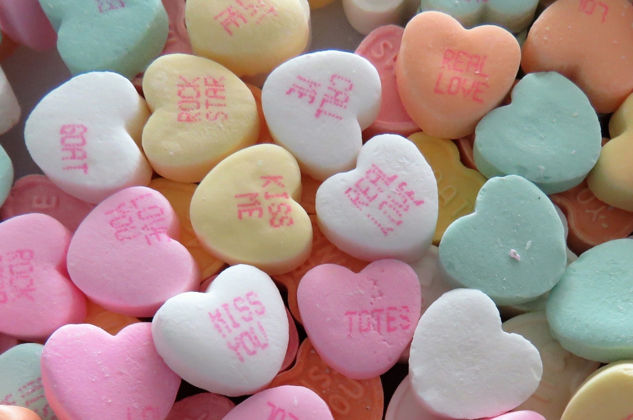Heart-shaped candy pieces with messages like "Kiss Me," "Real Love," and "Rock Star."