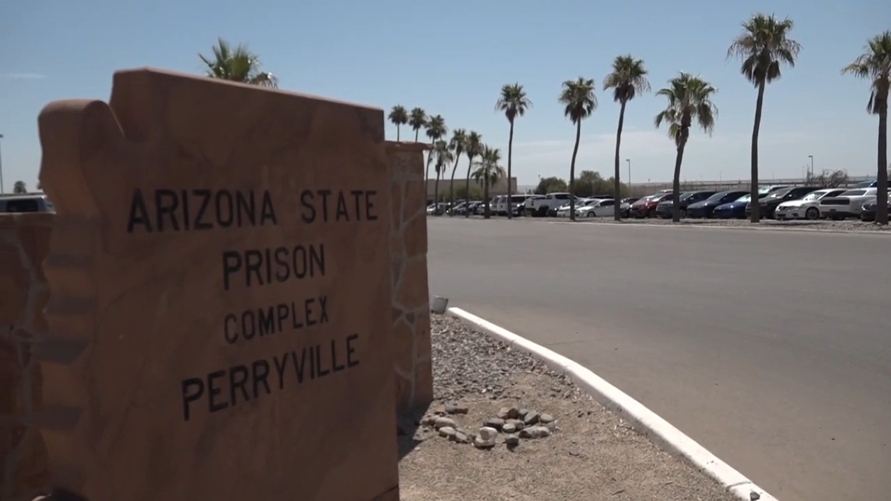 Skilt for Arizona State Prison Complex Perryville med palmer langs en parkeringsplass i bakgrunnen