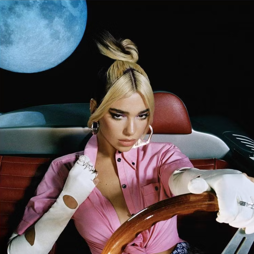 Person sitting successful  a car   with a stern expression, wearing a stylish top. Large satellite  successful  the inheritance  arsenic  portion  of the setting