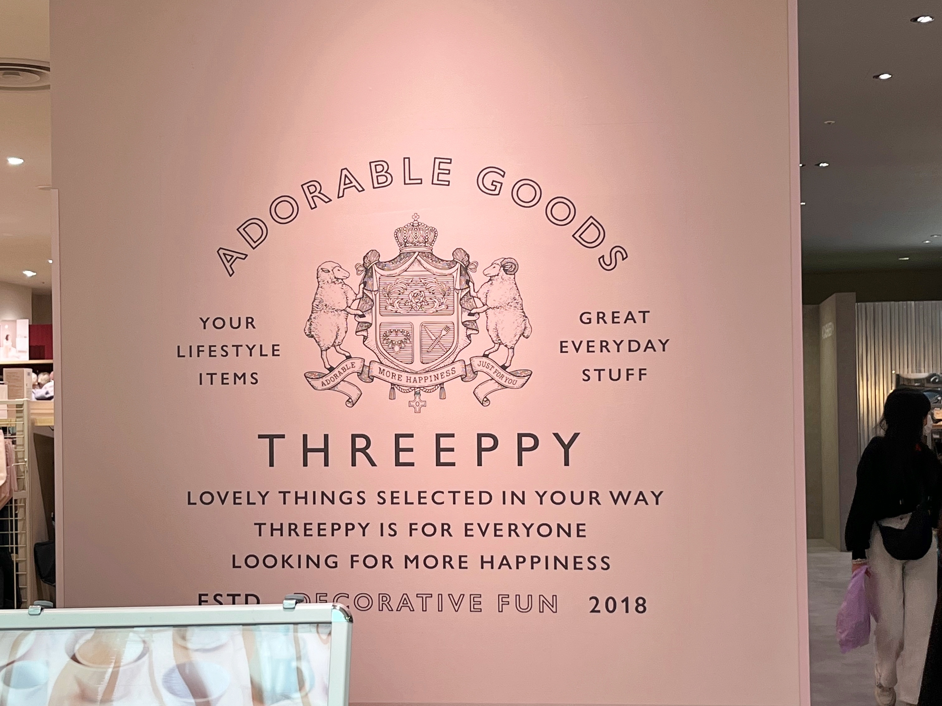 店内の壁に「ADORABLE GOODS THREEPPY」などの商品コンセプトを伝える英語のメッセージが表示されています。