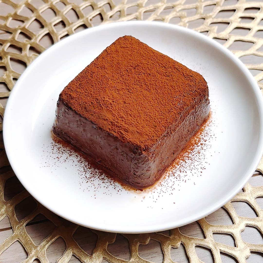 粉砂糖がかけられた角形のチョコレートムースが白い皿に盛られている。